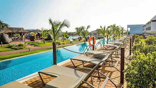 Liggestole ved en pool omgivet af palmer. (AI-genereret tekst)