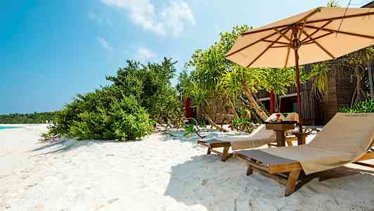 Liggestole på en sandstrand med parasol og planter. (AI-genereret tekst)