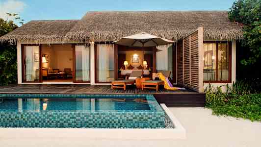 En strandvilla med privat pool og siddepladser på en træterrasse. (AI-genereret tekst)