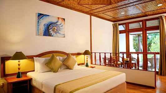 Et hotelværelse med en stor seng, to natborde med lamper og en siddegruppe ved vinduet. (AI-genereret tekst)