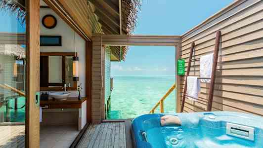 En udendørs terrasse med jacuzzi og udsigt over havet, samt interiør fra et badeværelse. (AI-genereret tekst)