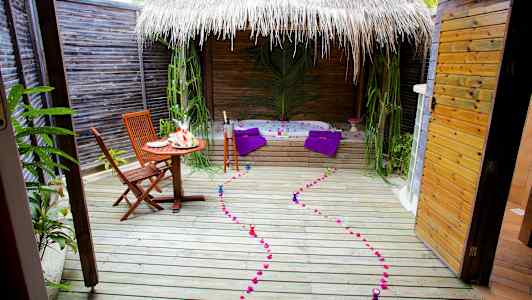 En udendørs terrasse med bord, stole, boblebad og dekorationer. (AI-genereret tekst)