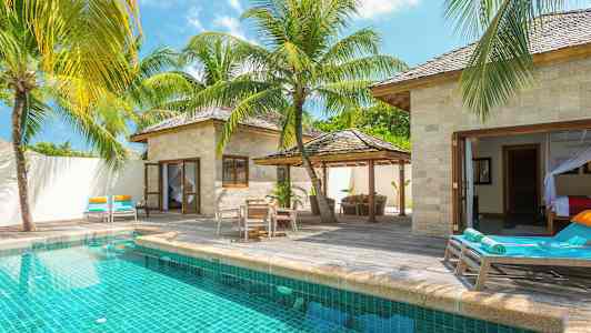 En villa med privat pool, omgivet af solsenge og tropiske palmer. (AI-genereret tekst)