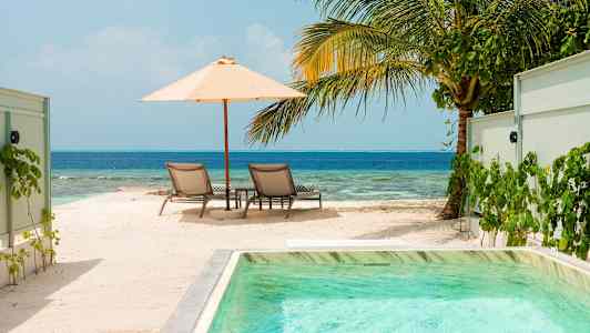 Solstole under parasol ved strand og hav. (AI-genereret tekst)