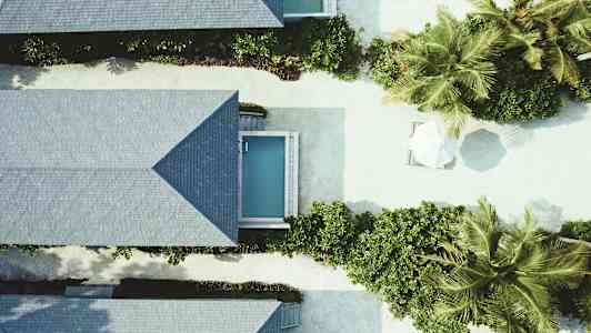 Luftfoto af ferieboliger med små pools og beplantning. (AI-genereret tekst)