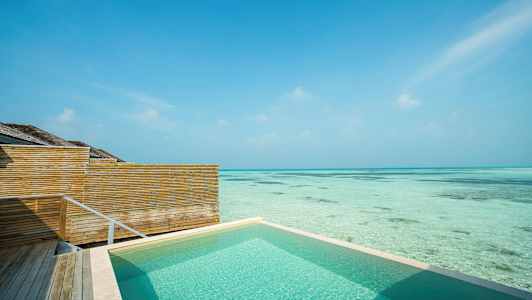 Swimmingpool ved havet med træhegn og klar blå himmel. (AI-genereret tekst)