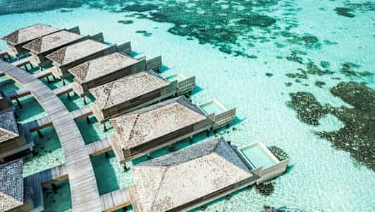 Bungalows på pæle med private pools over turkis vand. (AI-genereret tekst)