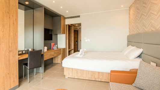 Et hotelværelse med en dobbeltseng, skrivebord og en siddeplads. (AI-genereret tekst)