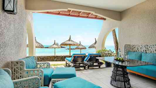 En terrasse med blå siddepladser og udsigt over havet med parasoller. (AI-genereret tekst)