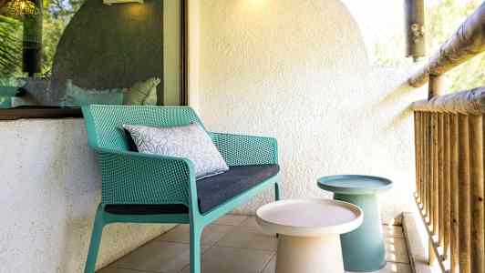 Terrasse med en grøn stol og små borde. (AI-genereret tekst)