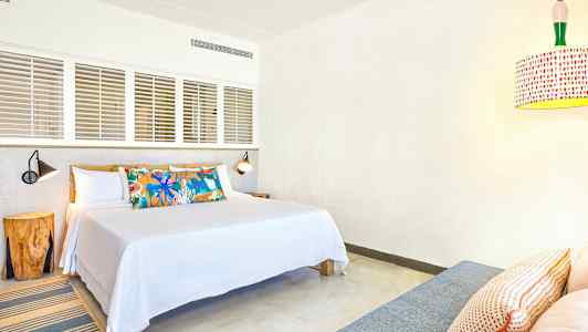 Et hotelværelse med en dobbeltseng, dekorativt pudemønster og moderne belysning. (AI-genereret tekst)