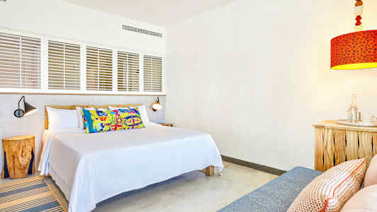 Et værelse med en seng, puder og en rød lampe. (AI-genereret tekst)