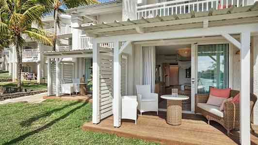 En terrasse med siddepladser ved en hvid bygning og græsplæne. (AI-genereret tekst)