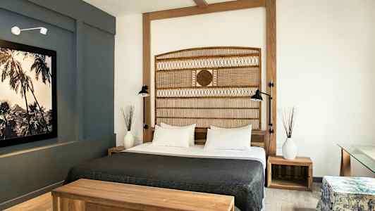 Et hotelværelse med en dobbeltseng, træmøbler og moderne indretning. (AI-genereret tekst)