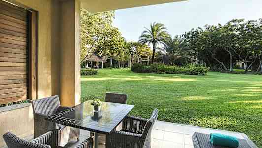 Udendørs område med bord og stole, udsigt til en frodig have. (AI-genereret tekst)