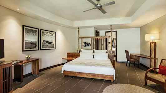 Moderne indrettet hotelværelse med dobbeltseng, skrivebord og stol, vægkunst og loftsventilator. (AI-genereret tekst)