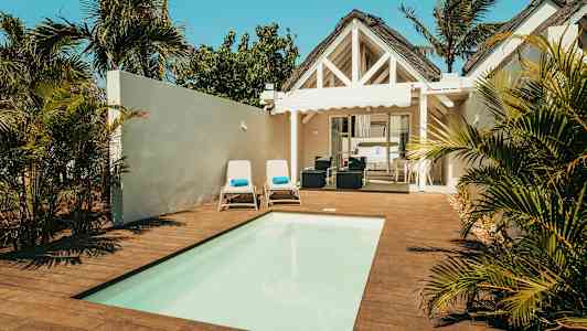 Villa med pool, liggestole og grønne omgivelser. (AI-genereret tekst)