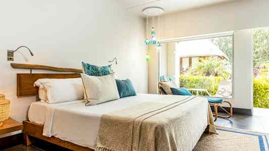 Et lyst soveværelse med en dobbeltseng og store vinduer ud mod en frodig have. (AI-genereret tekst)