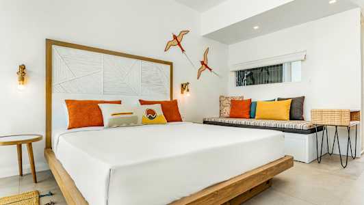 Moderne hotelværelse med dobbeltseng og farverige puder. (AI-genereret tekst)