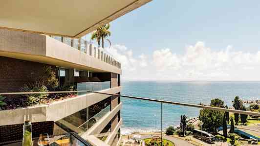 Udsigt fra balkon med hav og park. (AI-genereret tekst)