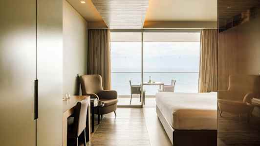 Moderne hotelværelse med havudsigt gennem store vinduer. (AI-genereret tekst)