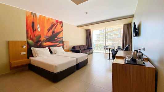 Hotelværelse med to enkeltsenge, sofa og altan med udsigt. (AI-genereret tekst)