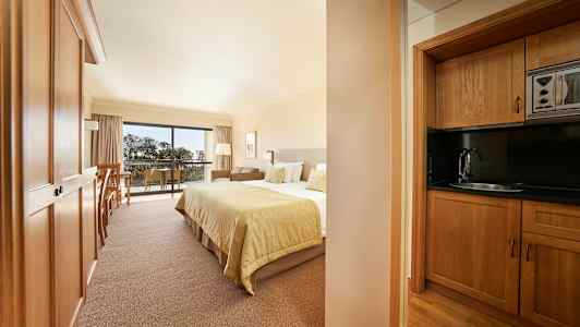 Billede af et hotelværelse med en seng og et køkken i træ. (AI-genereret tekst)