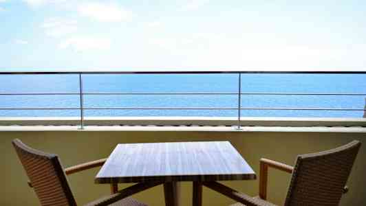 En udendørs terrasse med et bord og to stole, med udsigt over havet. (AI-genereret tekst)