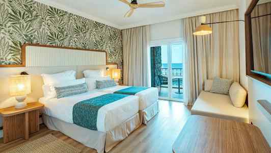 Hotelværelse med to enkeltsenge og en balkon med havudsigt. (AI-genereret tekst)