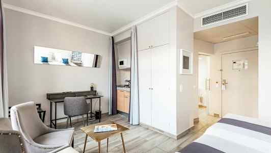 Værelse med siddepladser, skrivebord, seng og te-køkken. (AI-genereret tekst)