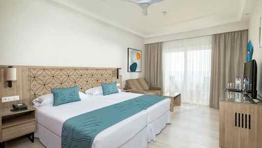 Billede af et hotelværelse med dobbeltseng, siddeområde og altan. (AI-genereret tekst)