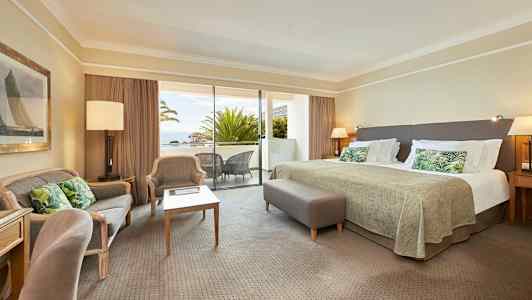 Et hotelværelse med stor seng, siddeområde og en balkon med udsigt. (AI-genereret tekst)