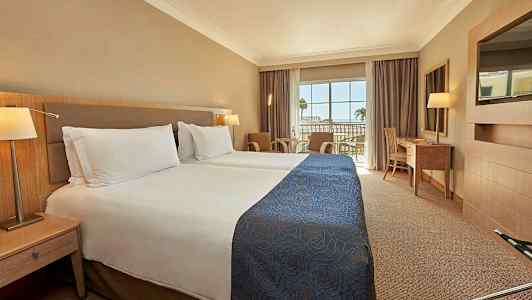 Hotelværelse med to enkeltsenge og en balkon med udsigt. (AI-genereret tekst)