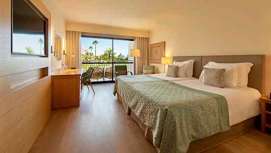 Moderne hotelværelse med dobbeltseng og altan i baggrunden. (AI-genereret tekst)