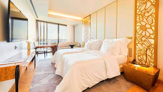 Billede af et moderne hotelværelse med to senge, siddeområde, møbler og dekorativ belysning. (AI-genereret tekst)