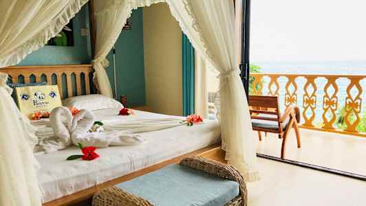 Et soveværelse med havudsigt, dekoreret med blomster på sengen. (AI-genereret tekst)