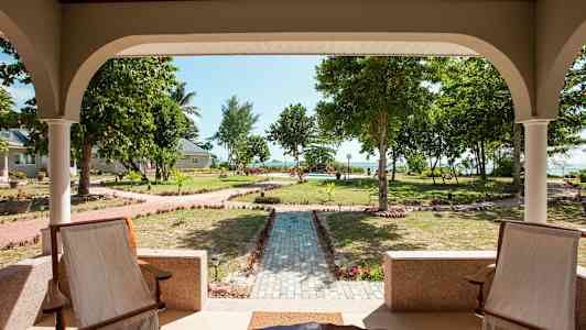 Udsigt fra en veranda mod en velplejet have med gangstier og træer. (AI-genereret tekst)