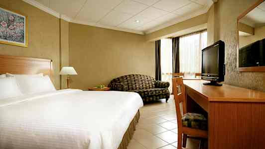 Hotelværelse med stor seng, skrivebord, TV og sofa. (AI-genereret tekst)