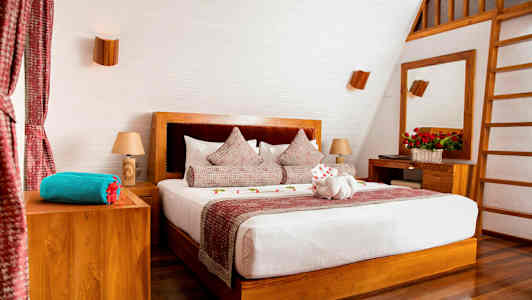 Et stilrent soveværelse med en dobbeltseng, trædetaljer og dekorerede puder. (AI-genereret tekst)