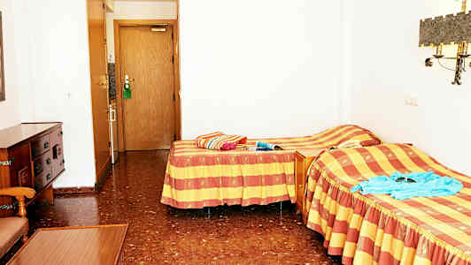 Et hotelværelse med to enkeltsenge og en dør til badeværelset. (AI-genereret tekst)