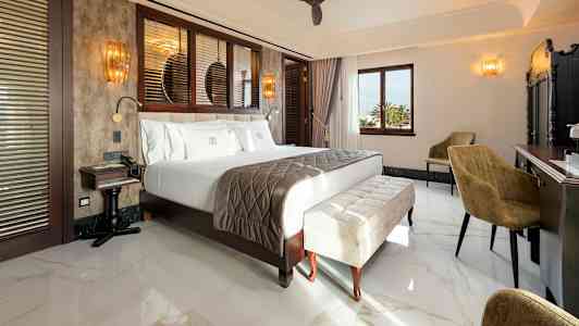 Et hotelværelse med en stor seng, siddepladser og et skrivebord. (AI-genereret tekst)