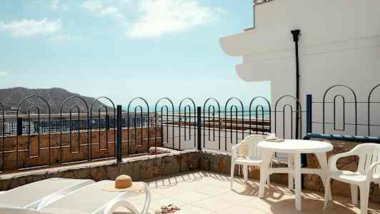 Terrasse med liggestole, bord og stole, havudsigt. (AI-genereret tekst)