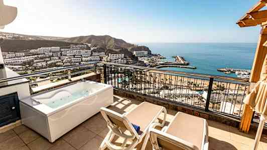 Altan med to liggestole og et boblebad, udsigt over havet og omgivelserne. (AI-genereret tekst)