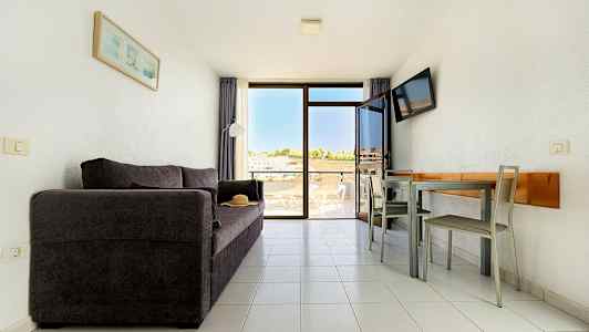 En stue med en mørk sofa, et spisebord med stole og en balkon med udsigt. (AI-genereret tekst)