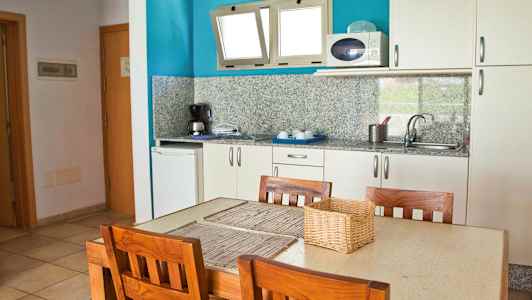 Et køkken med et bord og fire træstole. (AI-genereret tekst)