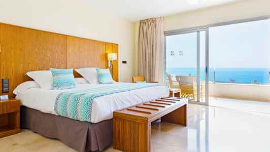 Dobbeltværelse med udsigt over havet gennem en stor glasrude. (AI-genereret tekst)