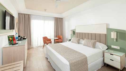 Hotelværelse med dobbeltseng, tv, siddeområde og garderobe. (AI-genereret tekst)