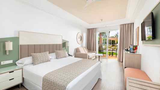 Et hotelværelse med dobbeltseng, sofa og glasdøre til en terrasse. (AI-genereret tekst)