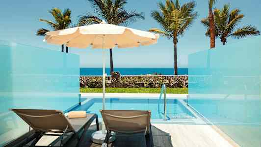 Billede af to liggestole og en parasol ved en privat pool med udsigt mod havet. (AI-genereret tekst)