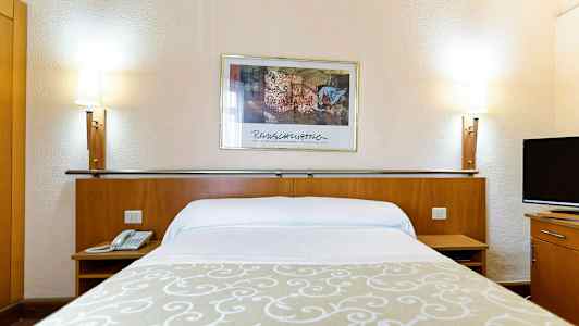 Hotelseng med hvide lagner, en beige dekoration, to sengelamper og et vægmaleri i baggrunden. (AI-genereret tekst)